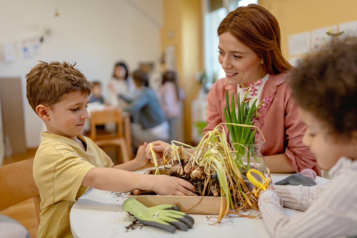 Teacher and curious children explore soil and plants in a classroom science activity