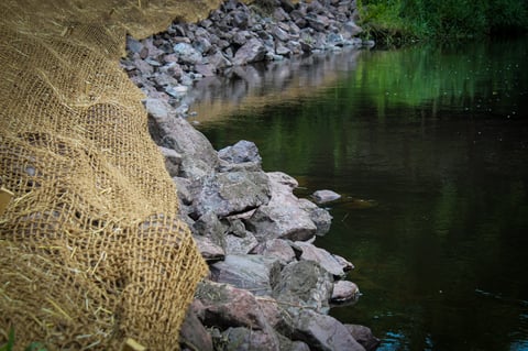 a bank stabilization project along a beautiful creek. watershed restoration with riprap and an erosion control blanket.