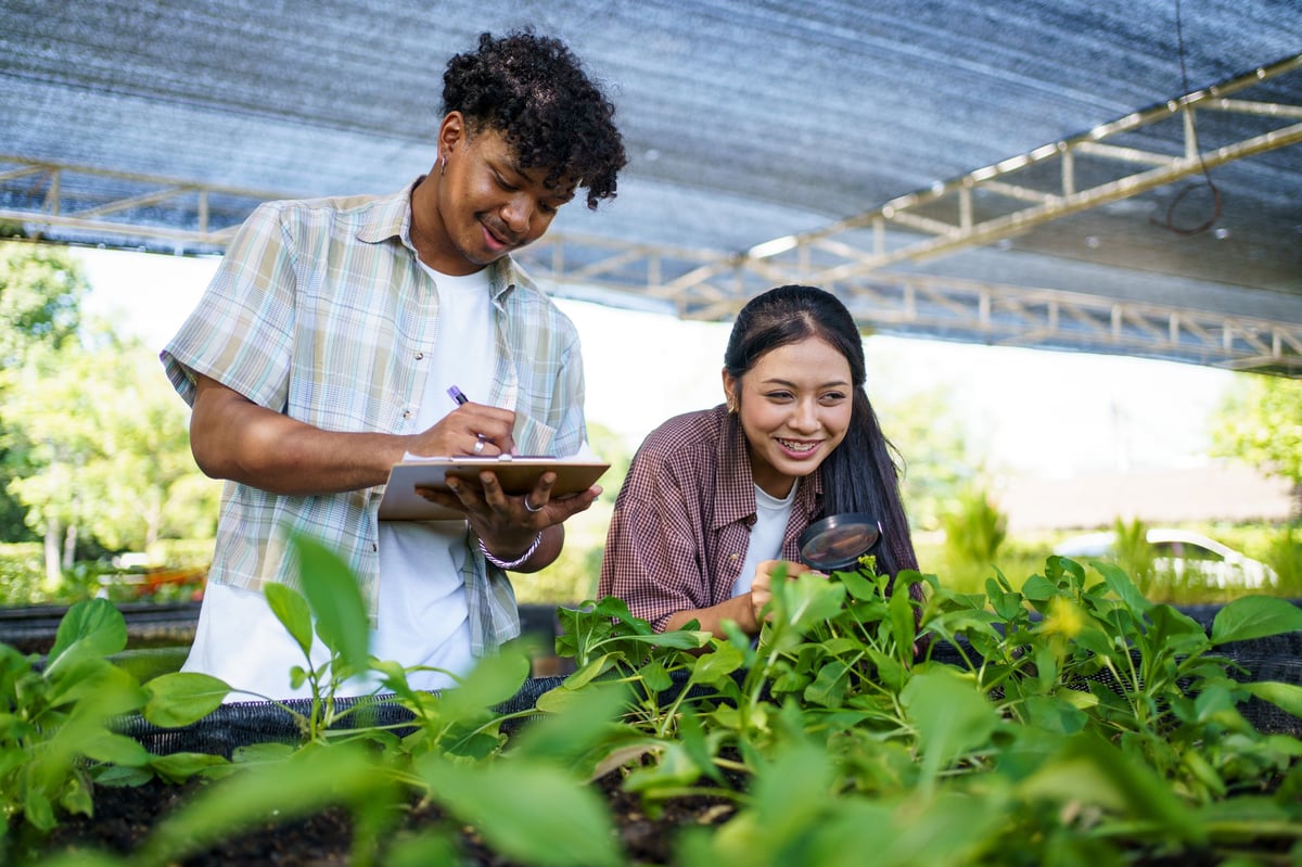 Students studying plant cultivation with focus and care, recording observations.