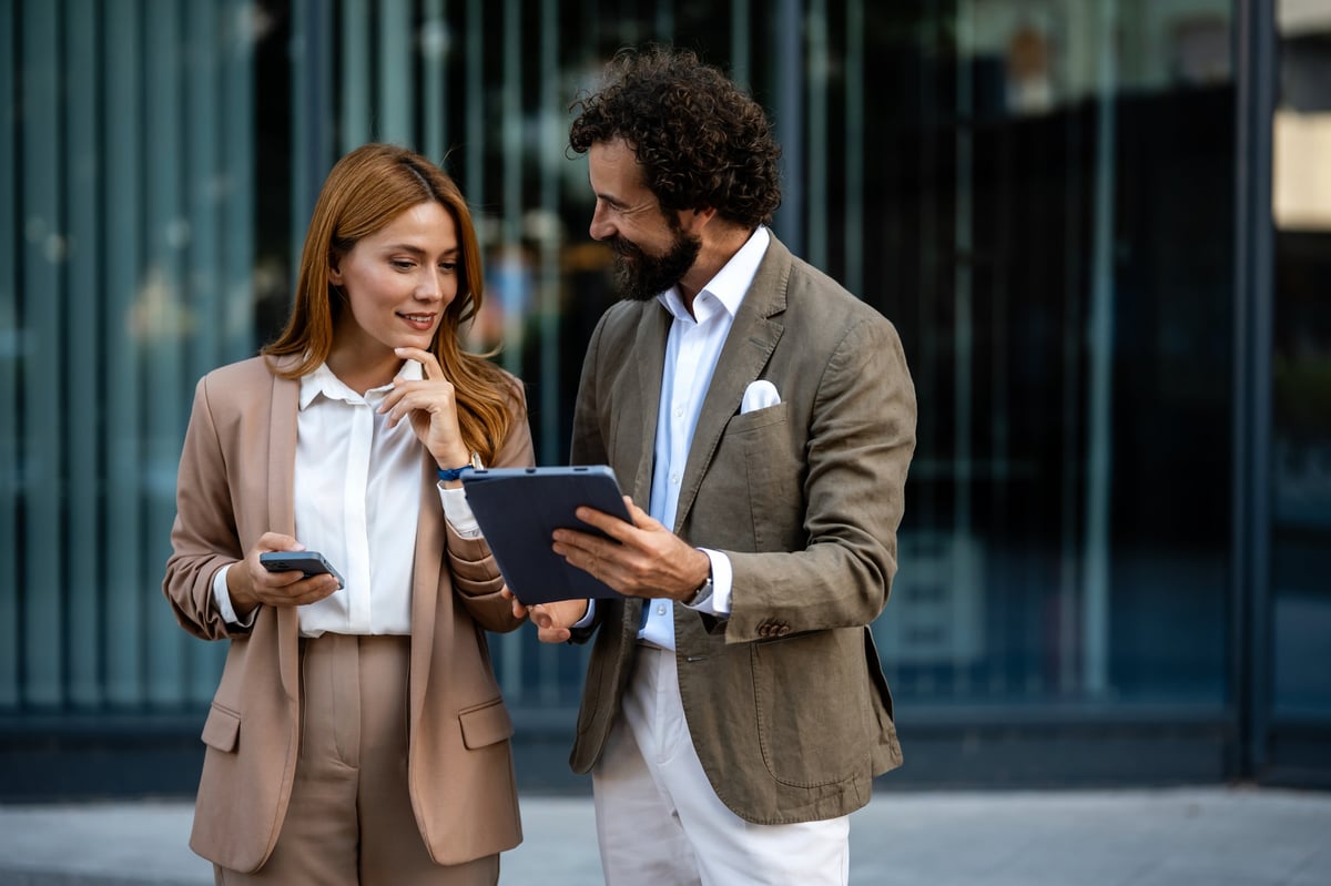 Business partners reviewing project details in front of modern office building