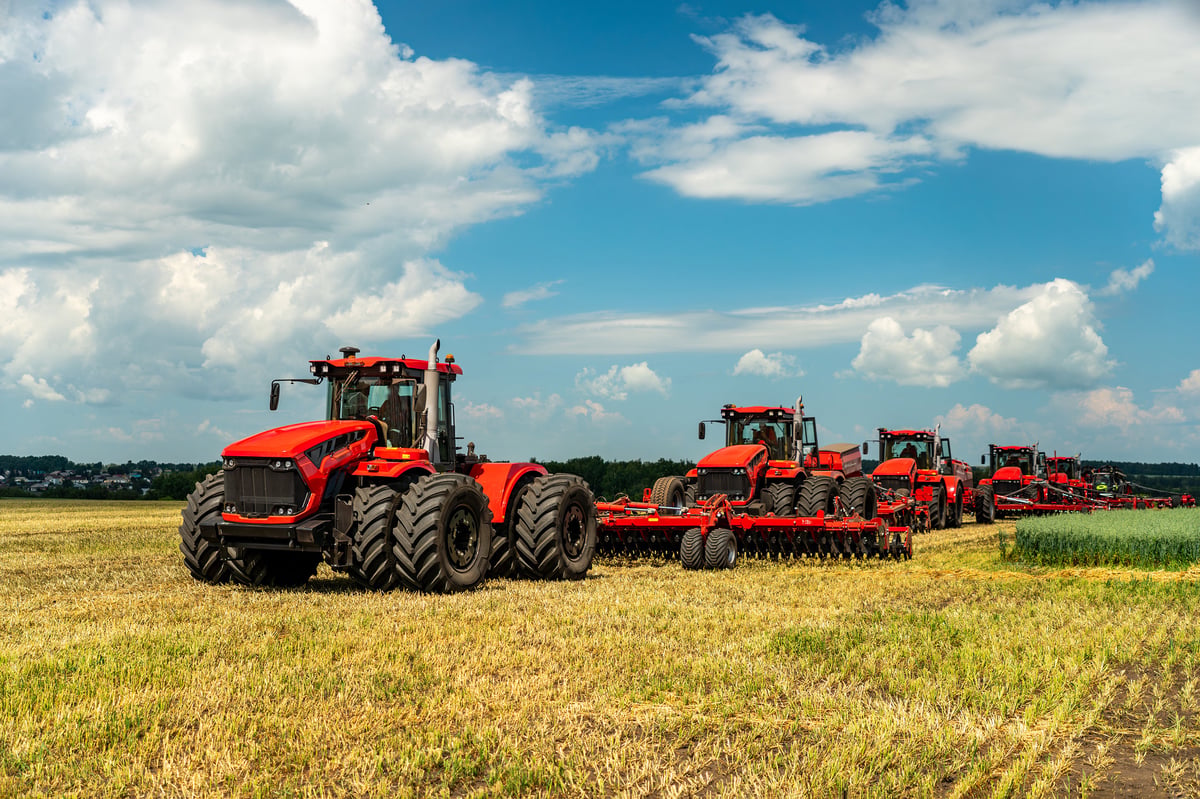 Agriculture. tractors on field against the background of blue clouds.