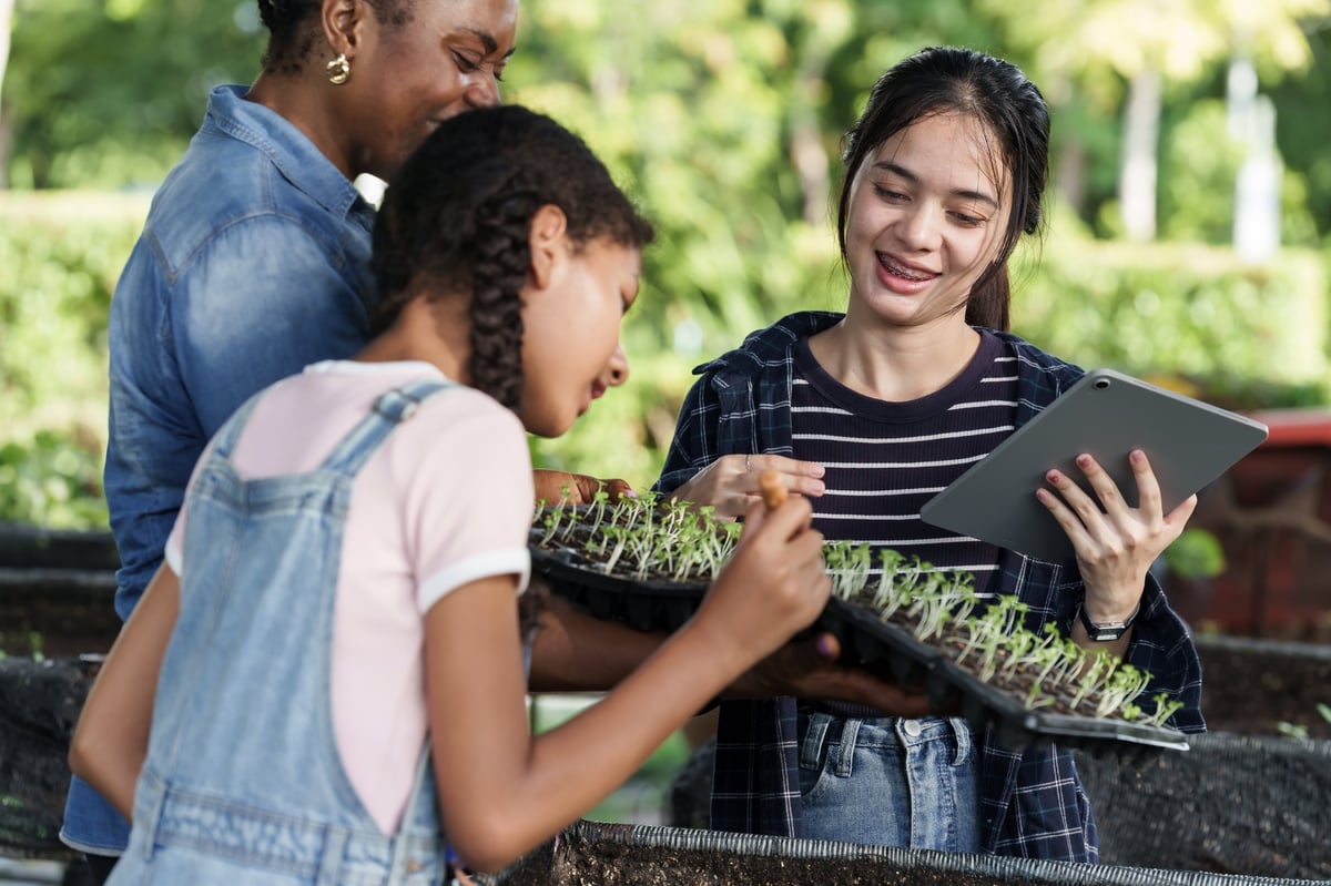 Group of diverse students and teacher participating in organic farming class at school garden