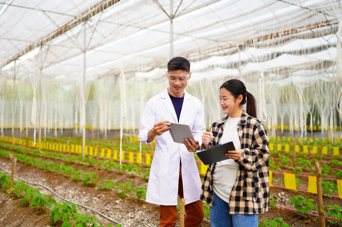 Practical agricultural studies of adolescent students, with scientists providing guidance, demonstrating hypotheses on soil sampling and data recording in greenhouse. Hands on training in high school.