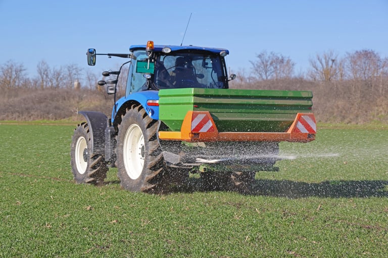Tractor and spreader working on wheat field, agricultural field application