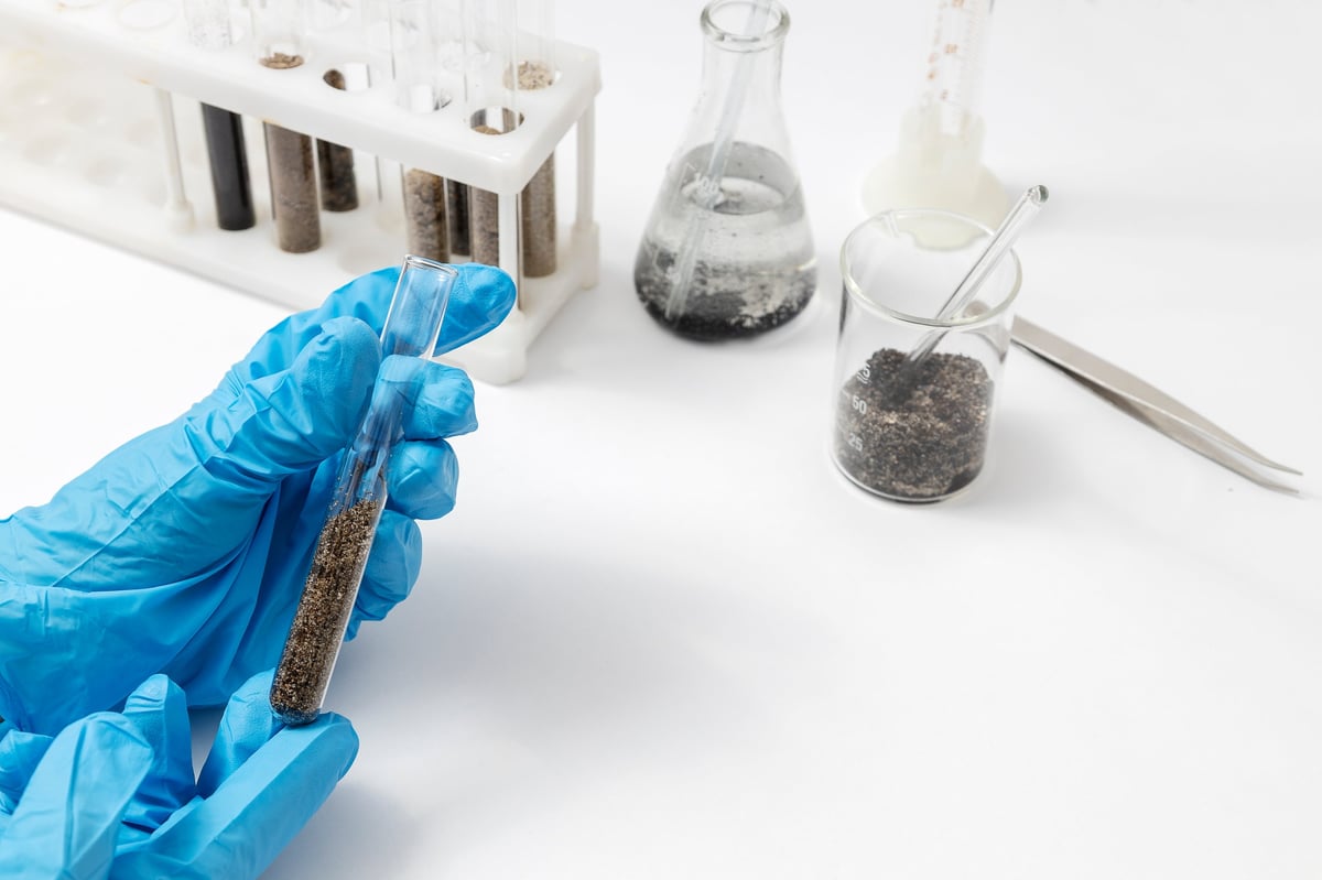 Soil testing process in a laboratory setting, showing samples in tubes and beakers with scientific tools for chemical and geological examination
