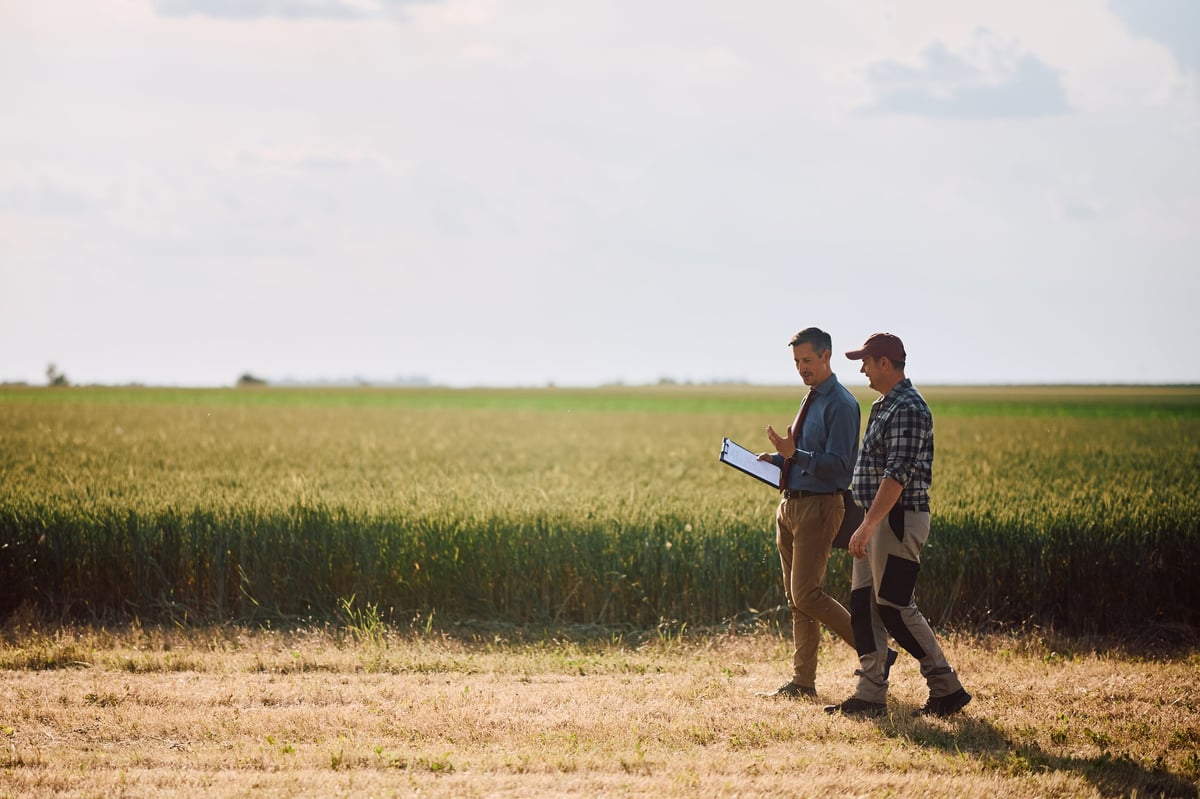 Producer and agricultural specialist walking and reviewing the field together outdoors