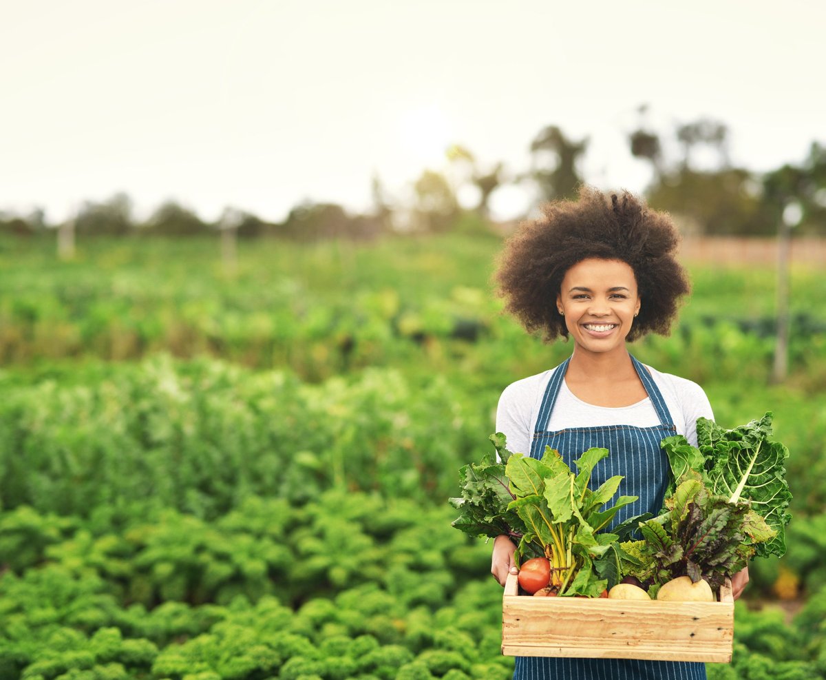 Cropped portrait of young female farmer carrying a crate of fresh produce
