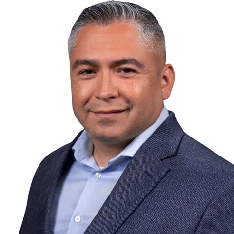 Professional headshot of a middle-aged man with gray hair wearing a dark blazer and light blue shirt against a white background