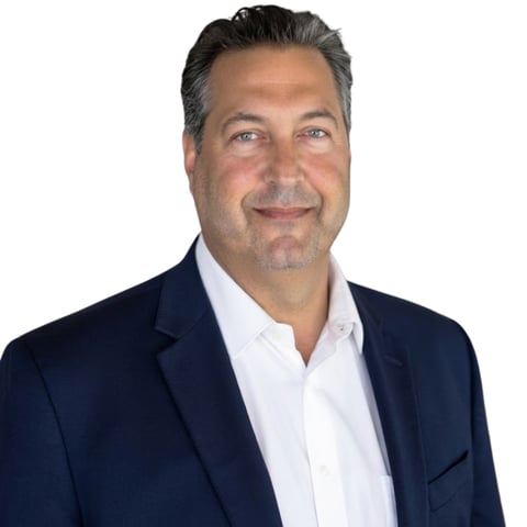 Professional headshot of a middle-aged man wearing a dark navy blazer and white shirt against a white background